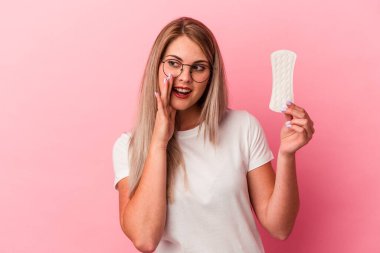 Pembe arka planda izole edilmiş kompres tutan genç Rus kadın gizli bir sıcak fren haberi veriyor ve yan bakıyor.