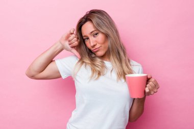 Pembe arka planda izole edilmiş pembe kupa tutan genç Avustralyalı kadın gururlu ve kendinden emin hissediyor, örnek olarak..