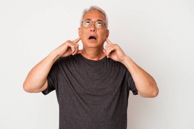 Beyaz arka planda izole edilmiş, kulakları parmaklarla kaplayan, stresli ve çaresiz kıdemli Amerikalı bir adam..