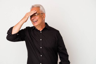 Beyaz arka planda izole edilmiş kıdemli Amerikalı adam elleriyle gözlerini kapatıyor, gülümseyerek büyük bir sürpriz bekliyor..