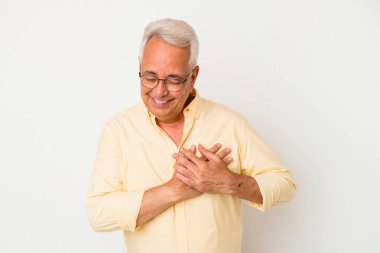 Beyaz arka planda izole edilmiş kıdemli Amerikalı adam, dost bir ifadeye sahip, avuçlarını göğsüne bastırıyor. Aşk konsepti.