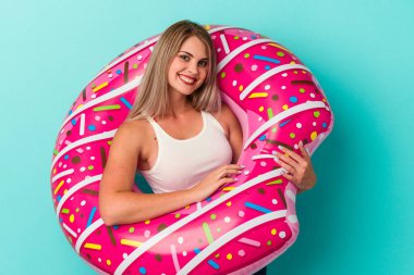 Şişme donutlu genç Rus kadın mavi arka planda izole edilmiş mutlu, güler yüzlü ve neşeli..