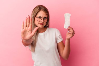 Genç Rus kadın pembe arka planda izole edilmiş bir kompres tutuyor elini uzatmış, dur işareti gösteriyor ve seni engelliyor..