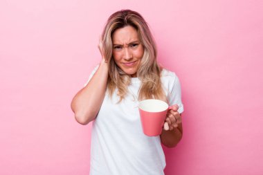 Pembe kupa tutan genç Avustralyalı kadın pembe arka planda izole edilmiş kulakları elleriyle kapatıyor..