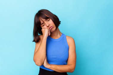 Mavi arka planda izole edilmiş genç melez kadın tekrarlanan bir görevden yoruldu..