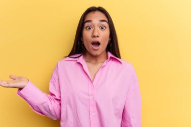 Sarı arka planda izole edilmiş genç melez kadın avuç içinde kopya alanı tutmaktan etkilenmiş..