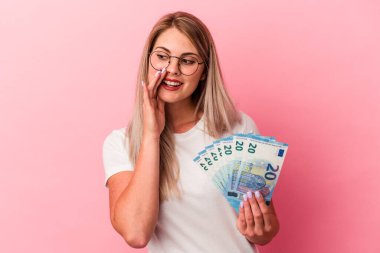 Pembe arka planda izole edilmiş banknotları tutan genç Rus kadın gizli bir sıcak fren haberinin olduğunu söylüyor.