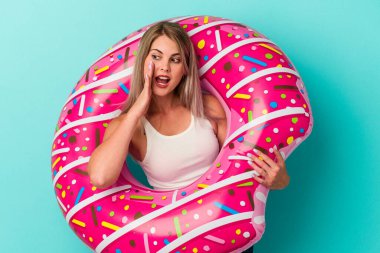 Şişme donutu olan genç bir Rus kadın mavi arka planda izole edilmiş bağırıyor ve avuç içini açık tutuyordu..