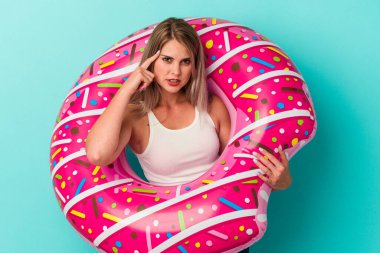 Mavi arka planda izole edilmiş şişme donutlu genç Rus kadın işaret parmağıyla yaptığı hayal kırıklığı jestini gösteriyor..