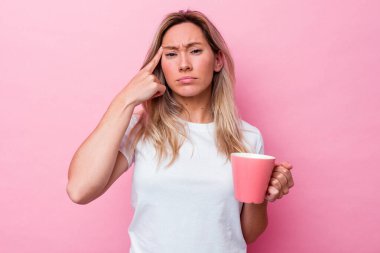 Pembe arka planda pembe kupa tutan genç Avustralyalı kadın işaret parmağıyla yaptığı hayal kırıklığı jestini gösteriyor..