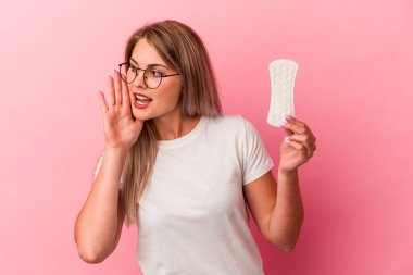 Genç Rus kadın pembe arka planda izole edilmiş bir kompres tutuyor bağırıyor ve avuç içini açık tutuyor..
