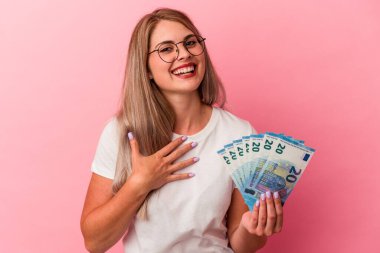 Pembe arka planda izole edilmiş banknotları tutan genç Rus kadın kahkahalarla gülüyor..