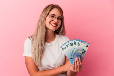 Pembe arka planda izole edilmiş faturaları tutan genç Rus kadın gülüyor ve eğleniyor..