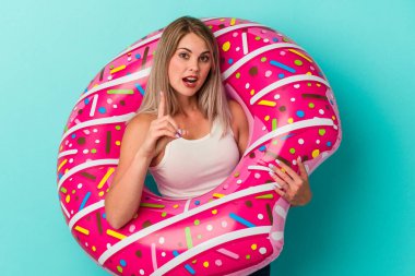 Şişme donutu olan genç Rus kadın mavi arka planda izole edilmiş. Harika bir fikri var, yaratıcılık kavramı..