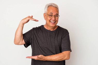 Beyaz arka planda izole edilmiş kıdemli Amerikalı adam işaret parmaklarıyla küçük bir şey tutuyor, gülümsüyor ve kendinden emin..