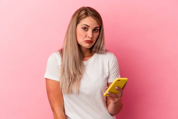 Ung Rysk Kvinna Som Håller Mobiltelefon Isolerad Rosa Bakgrund Axelryckningar — Stockfoto