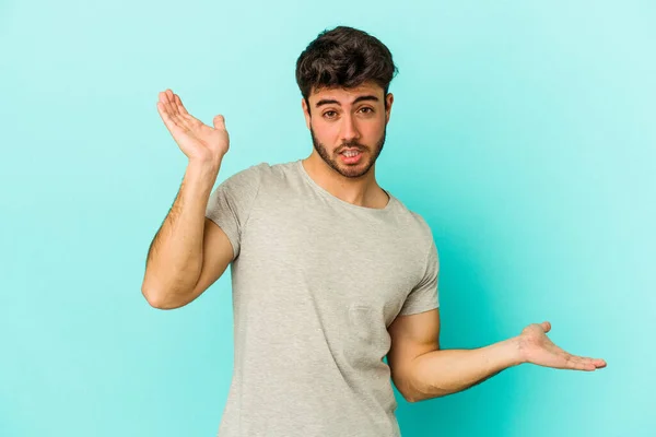 Jonge Blanke Man Geïsoleerd Blauwe Achtergrond Verward Twijfelachtige Schouders Een — Stockfoto