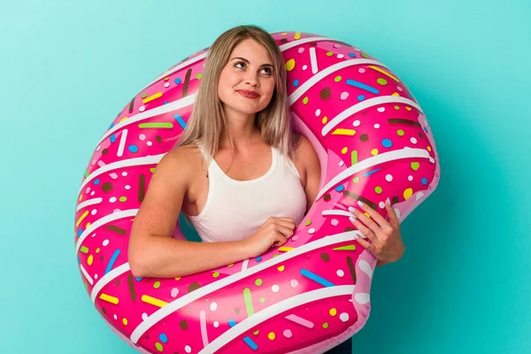 Şişme donutlu genç Rus kadın mavi arka planda izole edilmiş hedeflerine ve amaçlarına ulaşma hayali kuruyor.