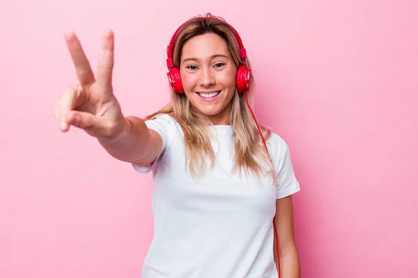 在粉红背景下听独立音乐的澳大利亚年轻女子 — 图库照片