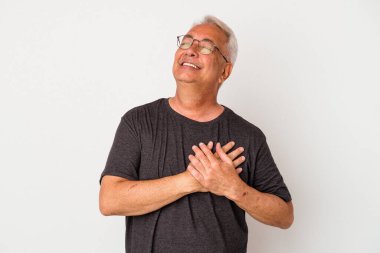 Beyaz arka planda izole edilmiş kıdemli Amerikalı adam gülüyor, ellerini yüreğine koyuyor, mutluluk kavramını koruyor..