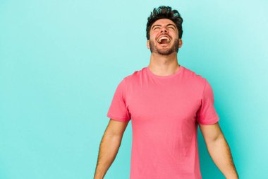 Kafkasyalı genç adam mavi arka planda izole edilmiş. Çok kızgın, öfkeli, hayal kırıklığına uğramış..