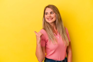 Genç Rus kadın sarı arka planda izole edilmiş başparmak uzakta, gülüyor ve kaygısız.