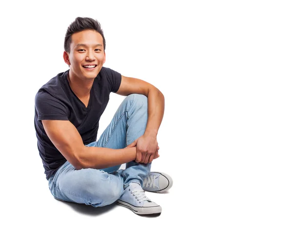 Asijský mladík sedící na podlaze — Stock fotografie