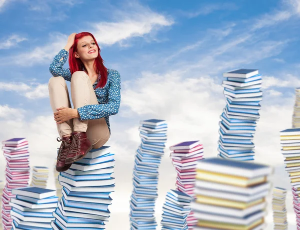 Jonge vrouw die op stapel boeken zit — Stockfoto