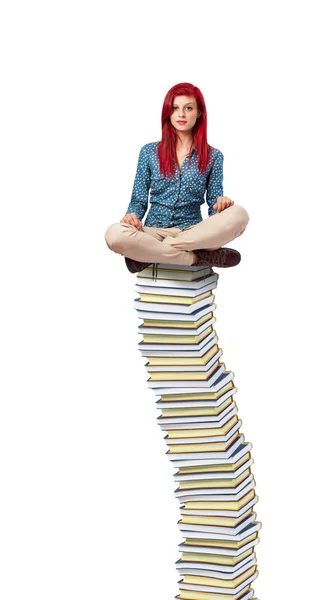 Kitaplar yığının üstüne oturan genç kadın — Stok fotoğraf