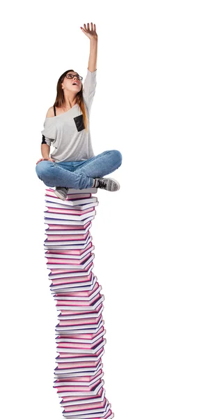 Молодая женщина сидит на книжной башне — стоковое фото