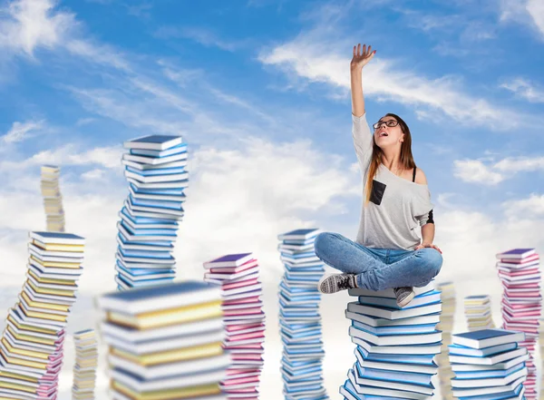 Giovane donna seduta sulla torre dei libri — Foto Stock