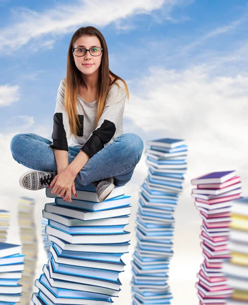 Młoda kobieta siedzi na wieży książek — Zdjęcie stockowe