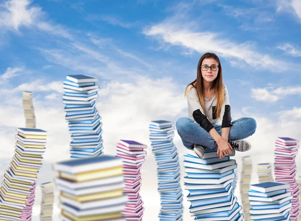 Young woman sitting on books tower — Stock Photo, Image