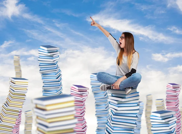 Young woman sitting on books tower — Stock Photo, Image