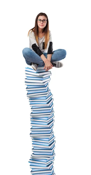 Jovem mulher sentada na torre dos livros — Fotografia de Stock