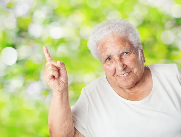 Old woman pointing up with finger — Stock Photo, Image