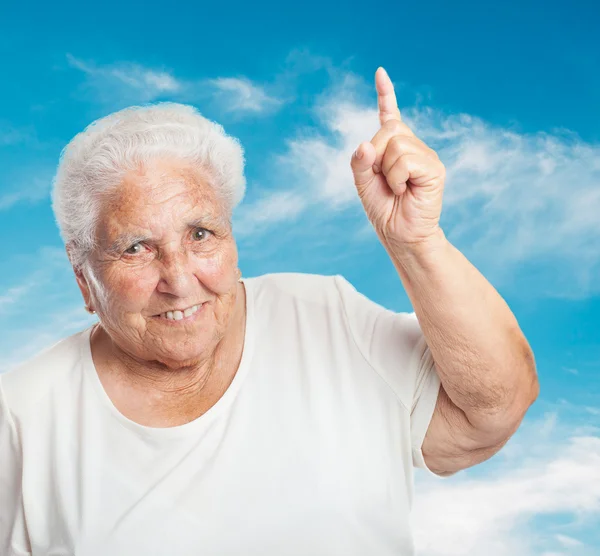 Alte Frau zeigt mit dem Finger nach oben — Stockfoto