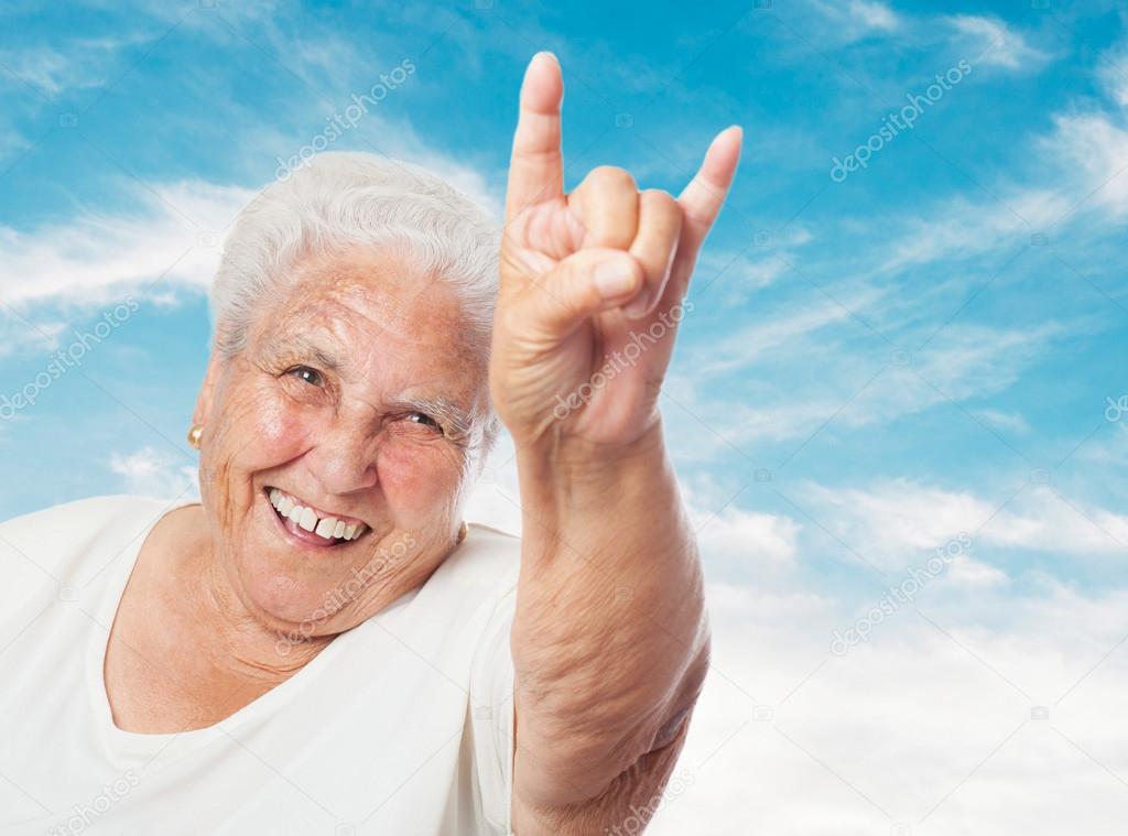 Old woman showing rock symbol