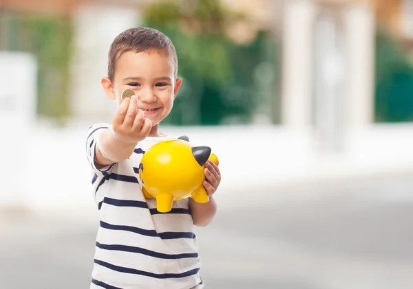 Little boy putting money into piggybank — Stock Photo, Image