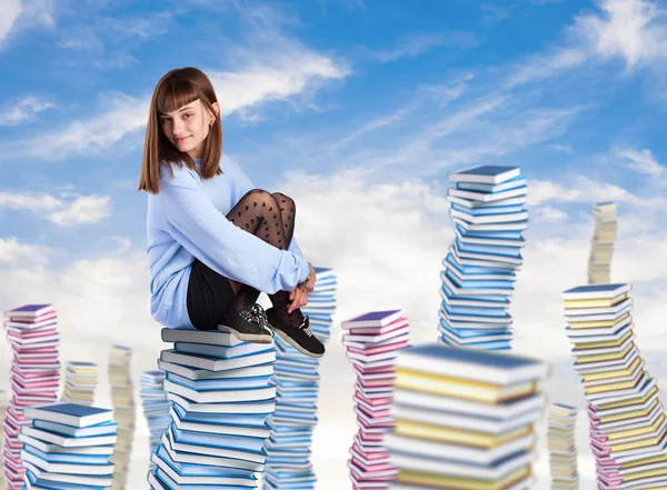 Mujer joven sentada en la torre de libros — Foto de Stock