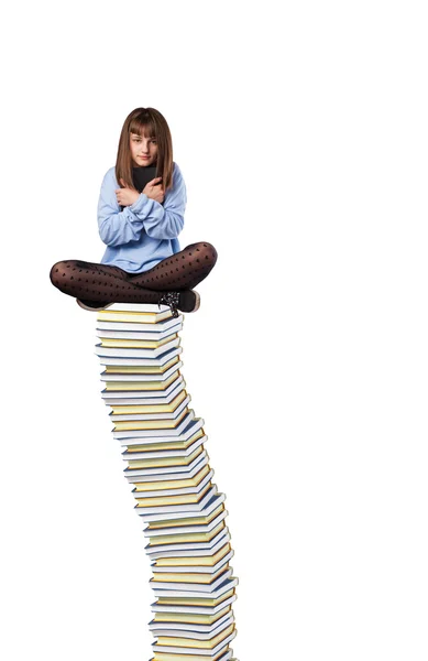 Young woman sitting on books pile — Stock Photo, Image