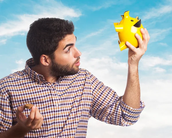 Handsome man looking into piggy bank — Stock Photo, Image