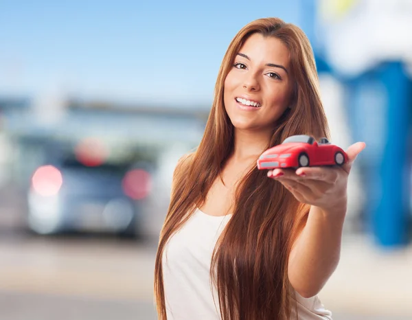 Mulher segurando um brinquedo de carro vermelho — Fotografia de Stock