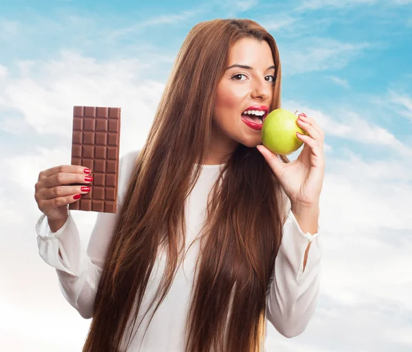 Frau isst einen Apfel statt einer Schokolade — Stockfoto