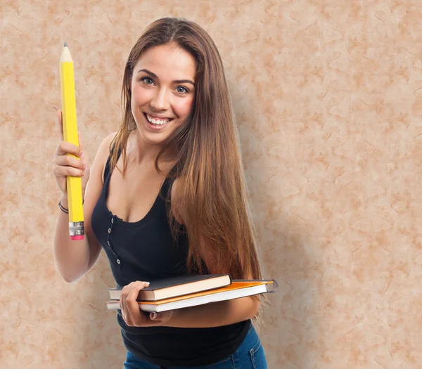 Student holding a big pencil and books — Stock Photo, Image