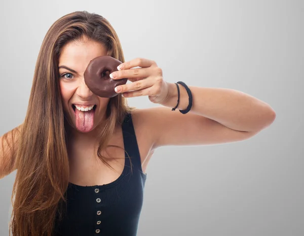 Vrouw op zoek via een chocolade donut — Stockfoto