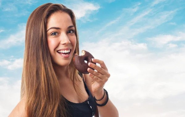 Mujer mordiendo un donut de chocolate — Foto de Stock