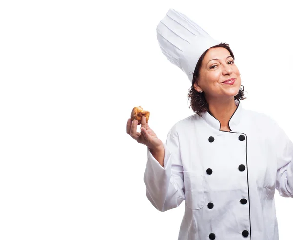 Mulher cozinheira madura comendo um cupcake — Fotografia de Stock