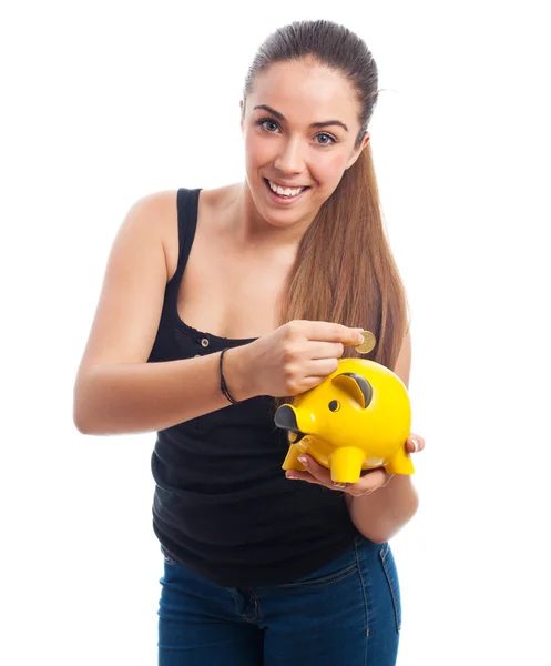 Woman inserting coin in a piggy bank — Stock Photo, Image