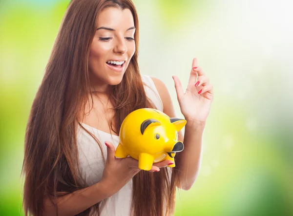 Girl inserting coin in a piggybank — Stock Photo, Image